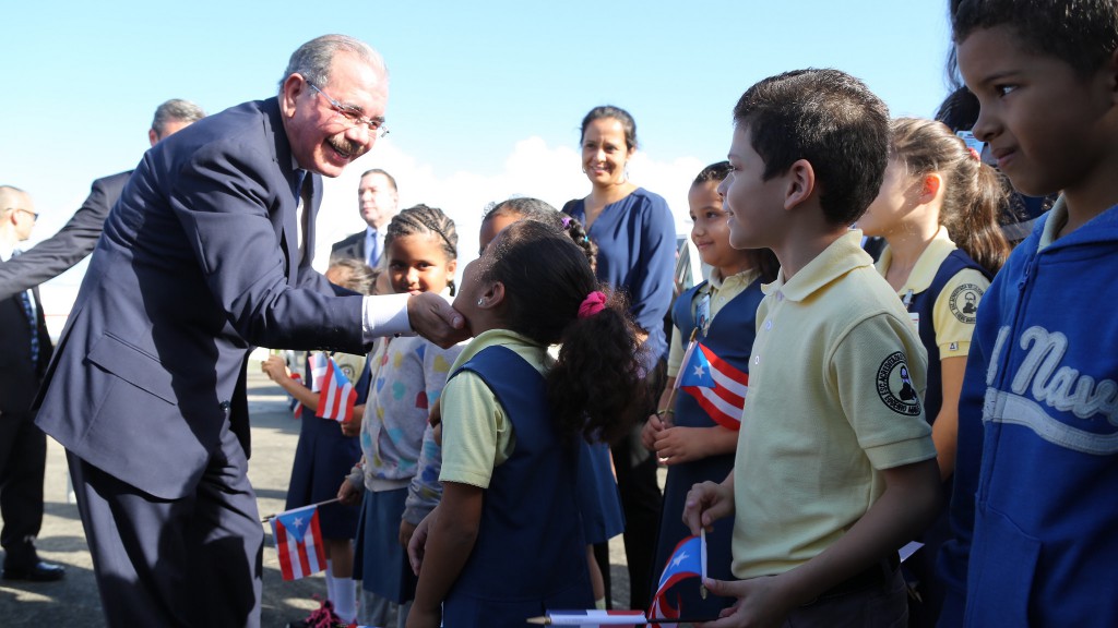 El mandatario dominicano saluda a niños a su llegada a la isla.