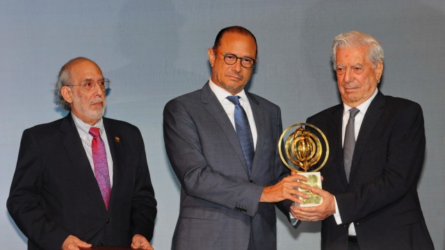 El escritor Mario Vargas Llosa recibe de manos del embajador ante la UNESCO el premio Pedro Henríquez Ureña. A su lado el comisario Luis O. Brea Franco.