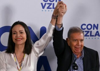 Venezuelan opposition leader Maria Corina Machado hold hands up with opposition presidential candidate Edmundo Gonzalez Urrutia in Caracas on July 29, 2024, a day after the Venezuelan presidential election. - Protests erupted in parts of Caracas Monday against the re-election victory claimed by Venezuelan President Nicolas Maduro but disputed by the opposition and questioned internationally, AFP journalists observed. (Photo by JUAN BARRETO / AFP)